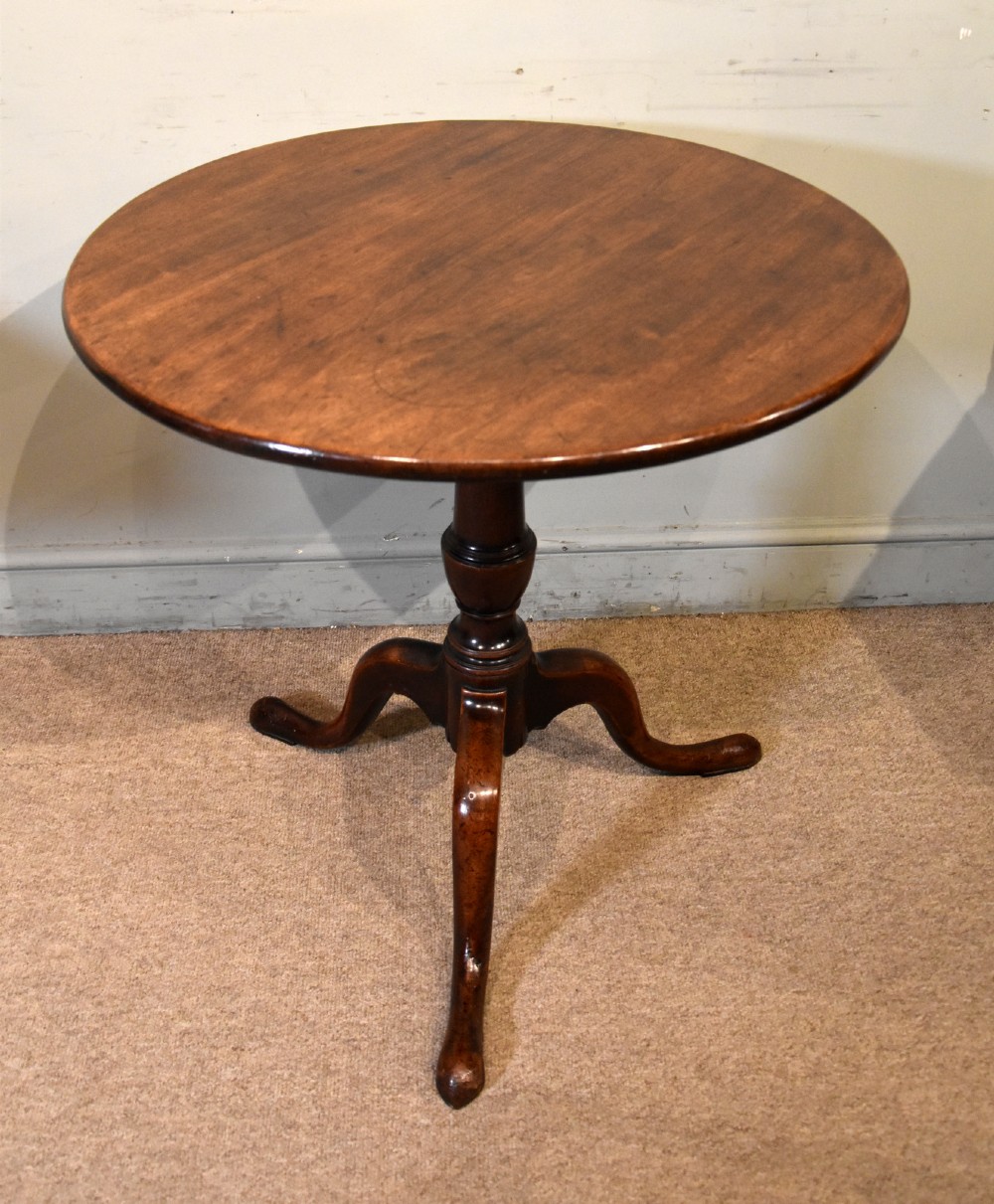 A George III mahogany tilt-top tripod table shown with its circular top tilted vertically on a turned stem and cabriole legs. View V
