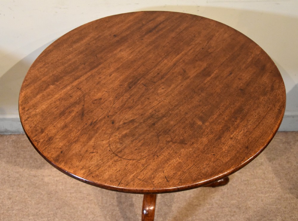 A George III mahogany tilt-top tripod table shown with its circular top tilted vertically on a turned stem and cabriole legs. View VI