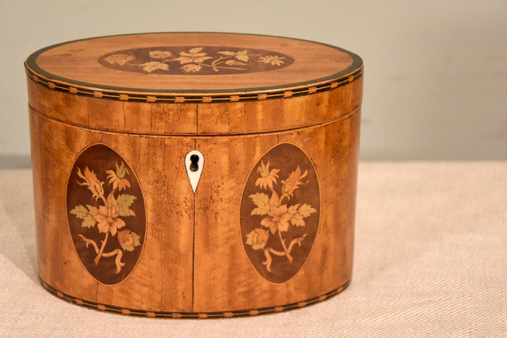 An 18th-century oval satinwood tea caddy featuring floral marquetry inlays, decorative stringing, and a bone keyhole escutcheon. View II