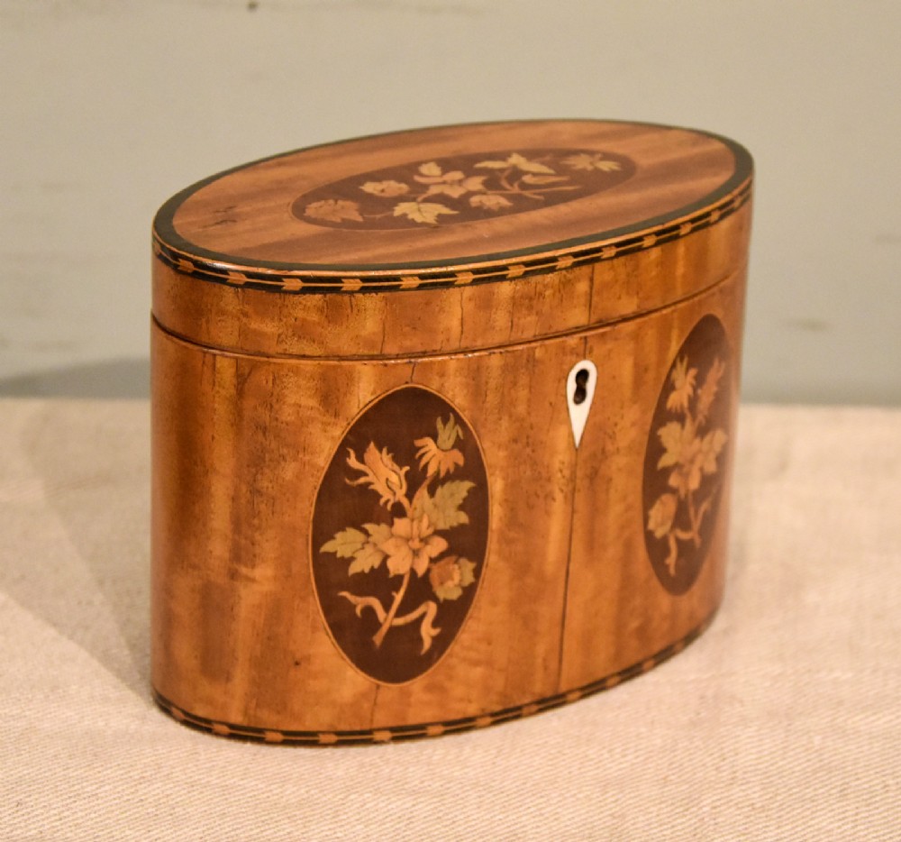 An 18th-century oval satinwood tea caddy featuring floral marquetry inlays, decorative stringing, and a bone keyhole escutcheon. View IV