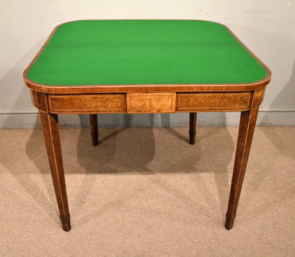 A George III fold-over card table with burr yew wood veneer, an oval central inlay, and square tapered legs. View II