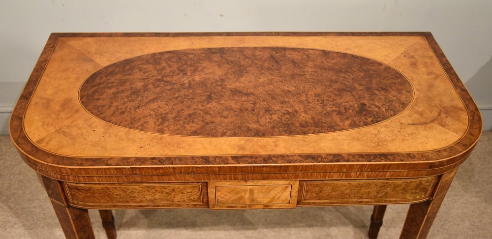 A George III fold-over card table with burr yew wood veneer, an oval central inlay, and square tapered legs. View V