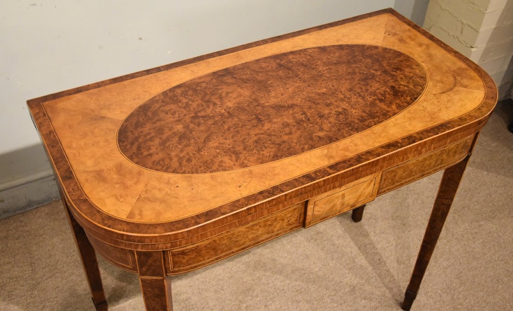 A George III fold-over card table with burr yew wood veneer, an oval central inlay, and square tapered legs. View VI