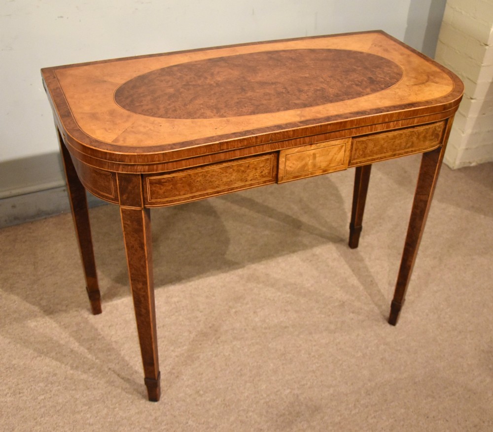 A George III fold-over card table with burr yew wood veneer, an oval central inlay, and square tapered legs. View VII