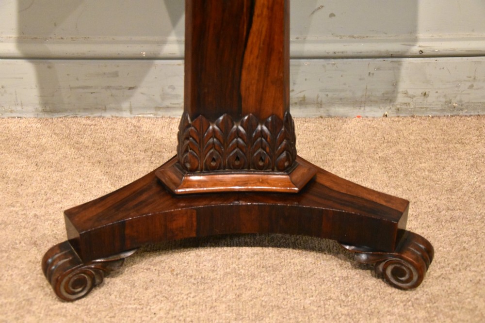 A William IV rosewood side table with a square top, plain frieze, tapered central pedestal, and a tri-form platform base on scroll feet. View V