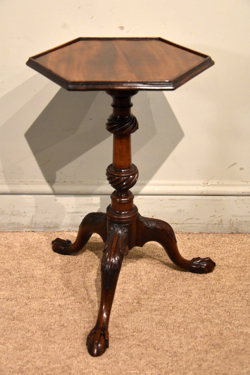 An 18th-century carved mahogany kettle stand with a hexagonal top, turned spiral column, and tripod cabriole legs ending in claw-and-ball feet.