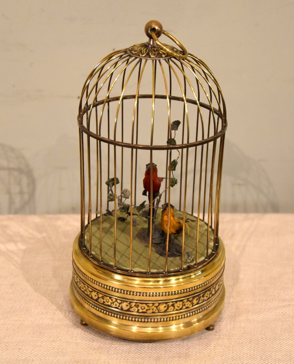 A Victorian brass birdcage automaton featuring two artificial feathered birds perched inside a domed wire cage over an embossed brass base. View III