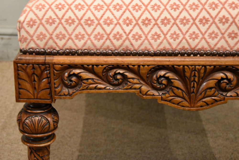 A Victorian rectangular rosewood dressing stool with patterned pink fabric upholstery, studding details, an acanthus-carved apron, and turned legs. View V