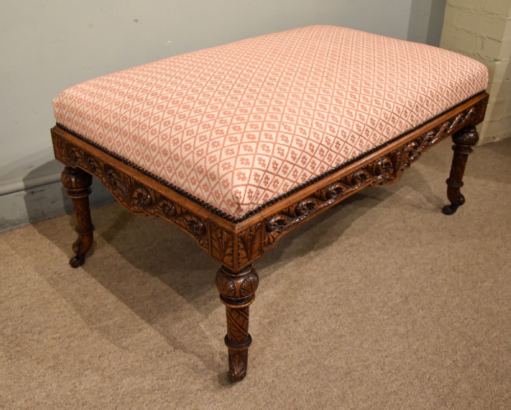 A Victorian rectangular rosewood dressing stool with patterned pink fabric upholstery, studding details, an acanthus-carved apron, and turned legs. View VI