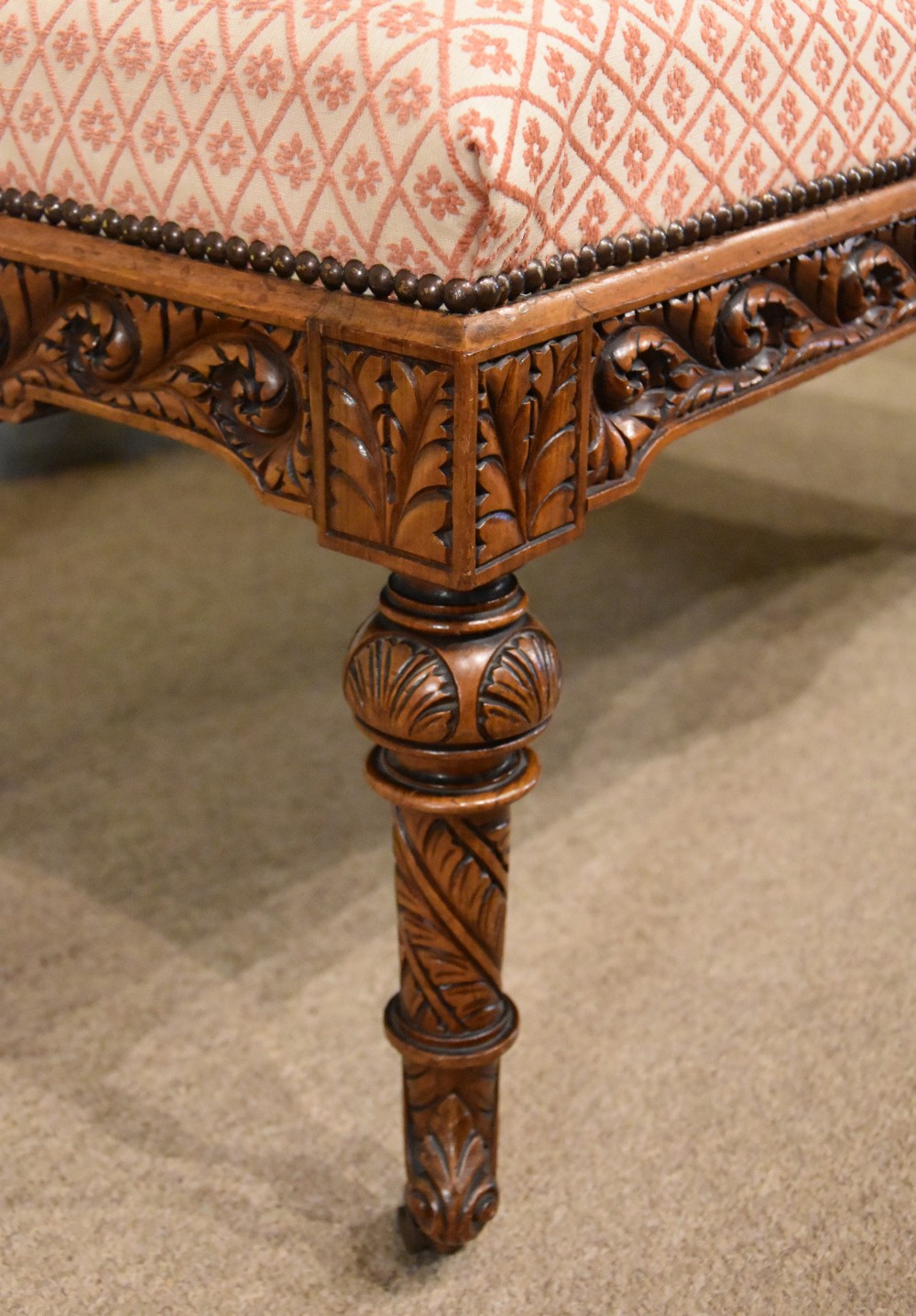 A Victorian rectangular rosewood dressing stool with patterned pink fabric upholstery, studding details, an acanthus-carved apron, and turned legs. View VII