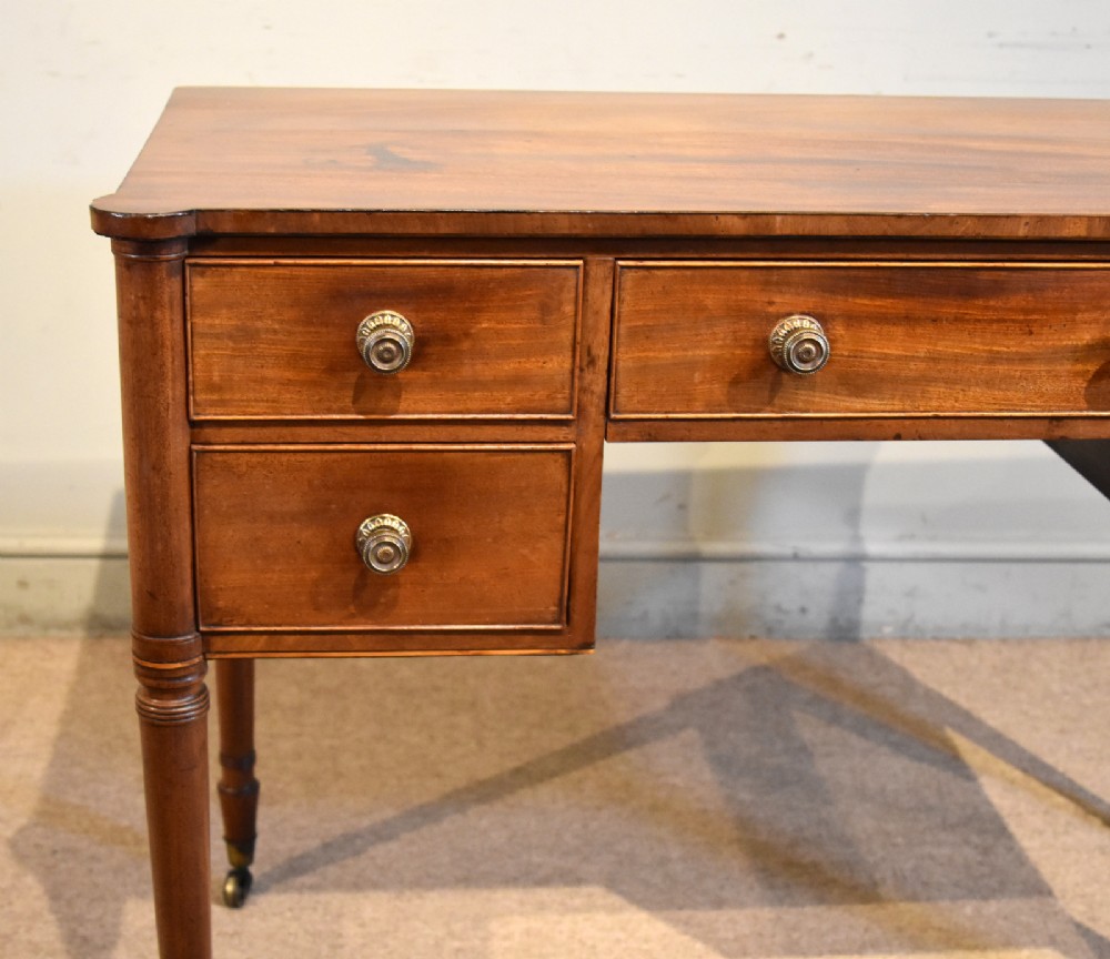 A Regency period mahogany dressing table featuring five drawers, circular brass handles, and turned tapered legs on brass castors. View VIII