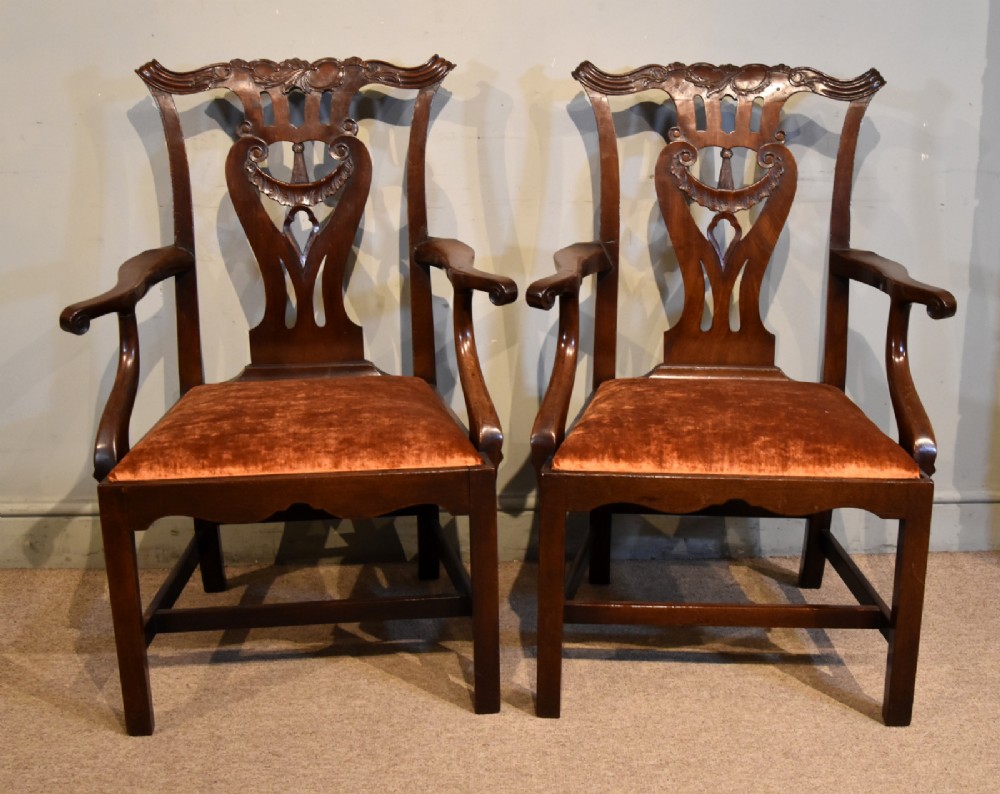 A pair of 18th-century mahogany Irish Chippendale armchairs featuring hand-carved pierced splats, curved arms, and rust-coloured velvet seat pads. View II