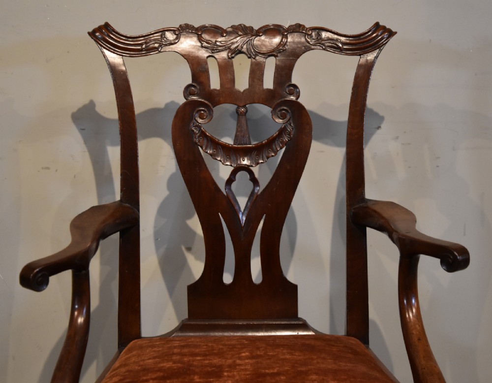 A pair of 18th-century mahogany Irish Chippendale armchairs featuring hand-carved pierced splats, curved arms, and rust-coloured velvet seat pads. View V