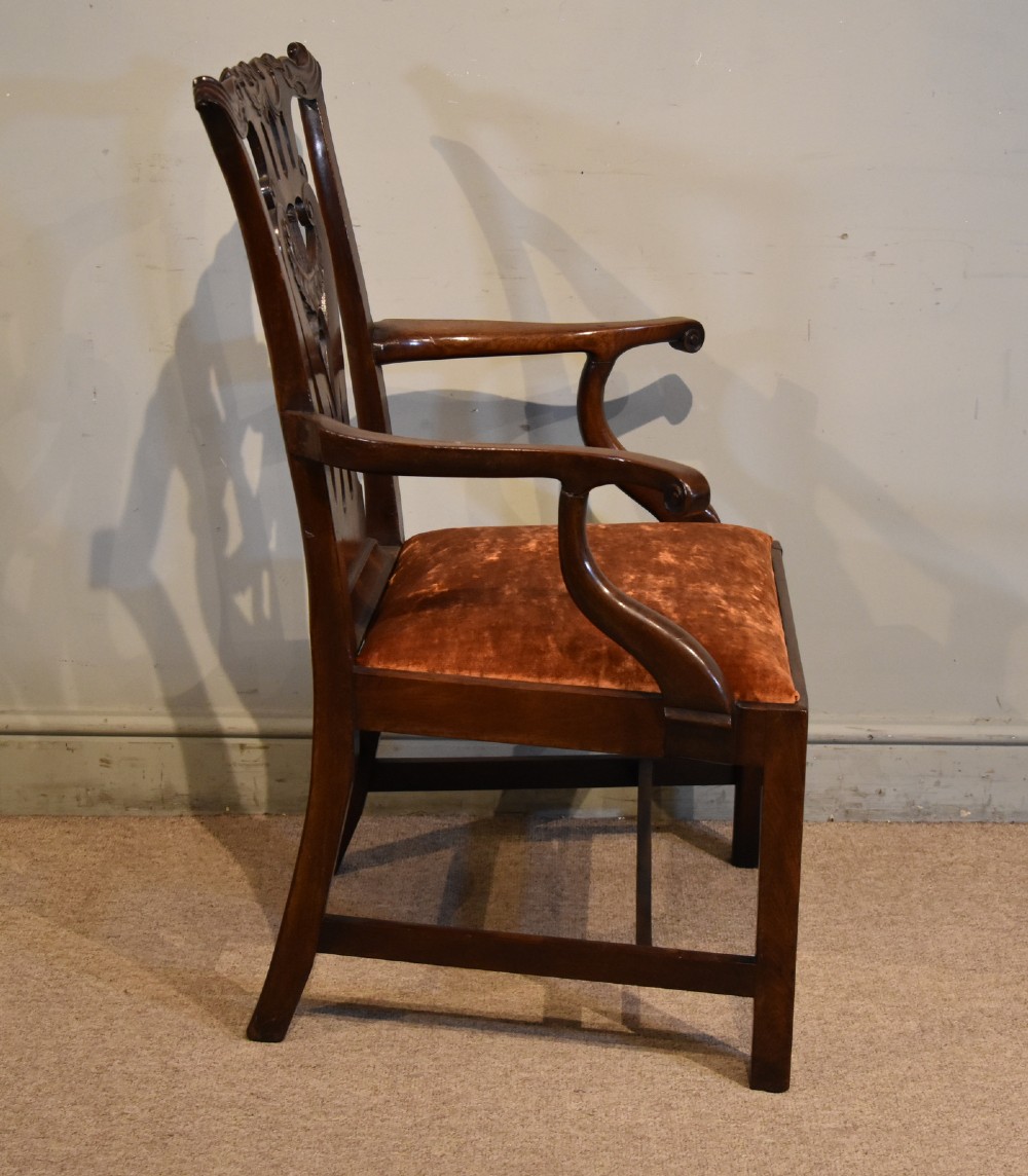 A pair of 18th-century mahogany Irish Chippendale armchairs featuring hand-carved pierced splats, curved arms, and rust-coloured velvet seat pads. View VI