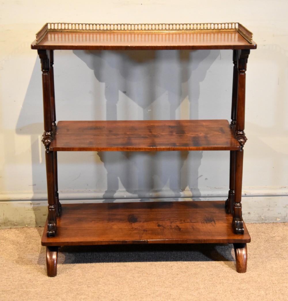 A mid nineteenth-century dark rosewood three-tier whatnot with turned support columns and a pierced brass gallery around the top shelf. View II