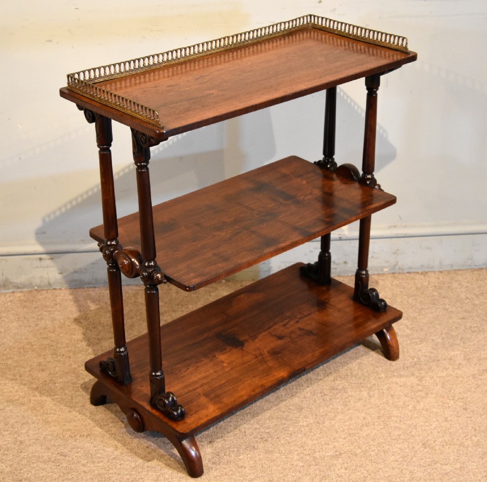 A mid nineteenth-century dark rosewood three-tier whatnot with turned support columns and a pierced brass gallery around the top shelf. View IV