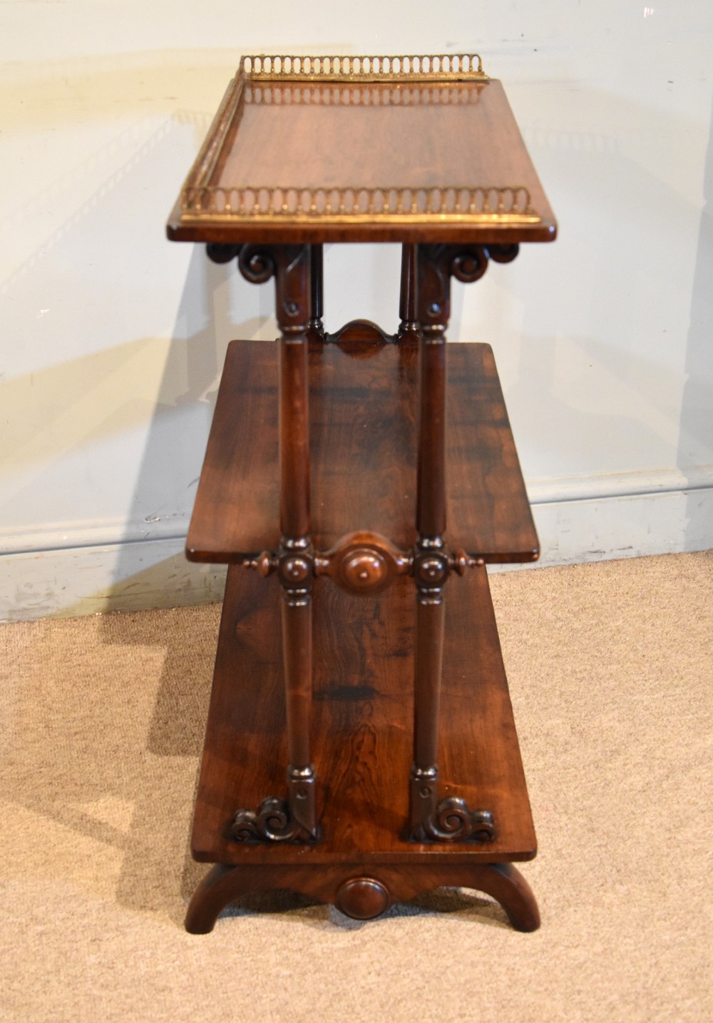 A mid nineteenth-century dark rosewood three-tier whatnot with turned support columns and a pierced brass gallery around the top shelf. View V