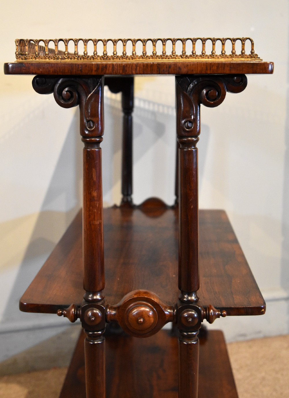 A mid nineteenth-century dark rosewood three-tier whatnot with turned support columns and a pierced brass gallery around the top shelf. View VII