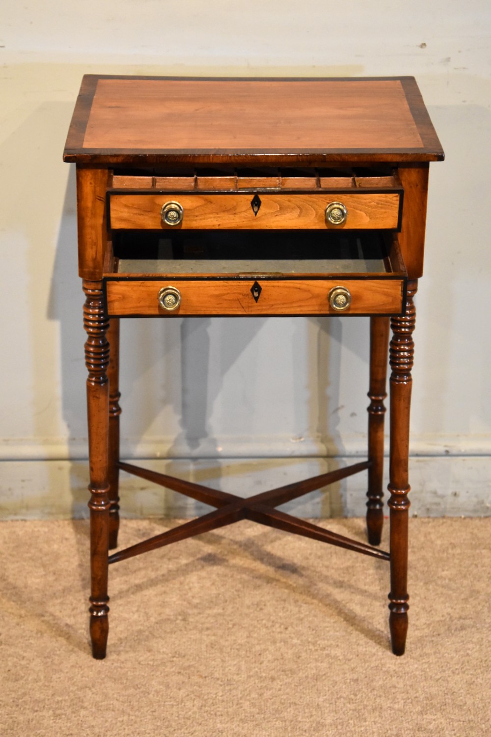 A Regency fruitwood side table featuring two small drawers with round brass knobs, rosewood cross-banding, turned legs, and an X-frame stretcher. View II