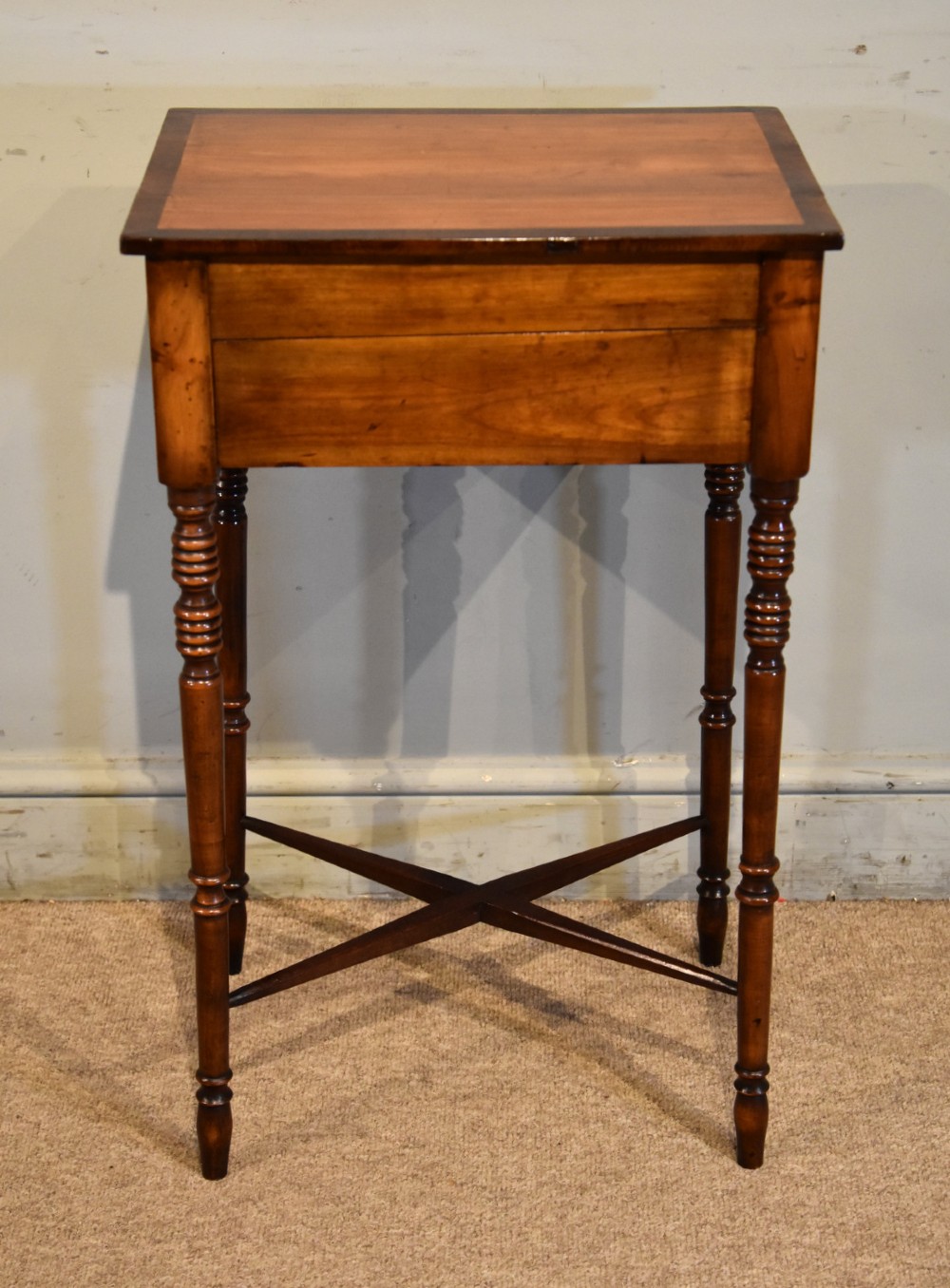 A Regency fruitwood side table featuring two small drawers with round brass knobs, rosewood cross-banding, turned legs, and an X-frame stretcher. View V