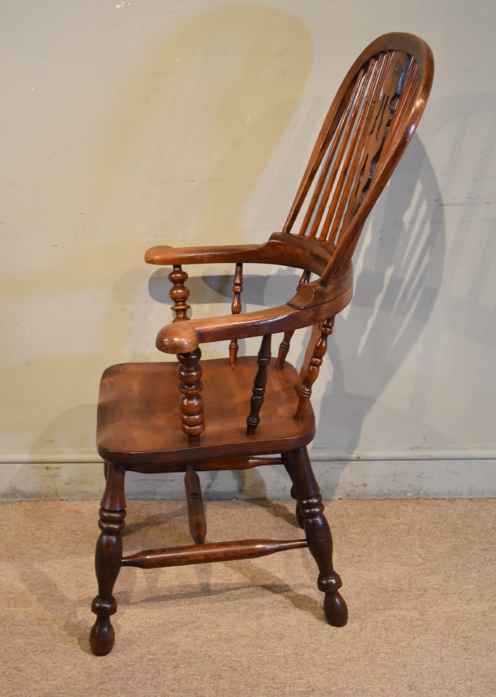 A 19th-century hoop-back Windsor armchair featuring turned wood spindles, a central pierced splat, a contoured saddle seat, and turned legs with an H-stretcher. View V