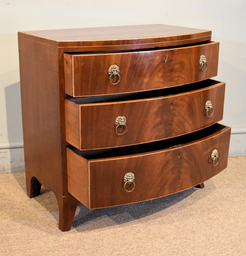 A Regency miniature bow-fronted chest of drawers made from flame mahogany with brass lion mask ring handles and boxwood stringing. View III