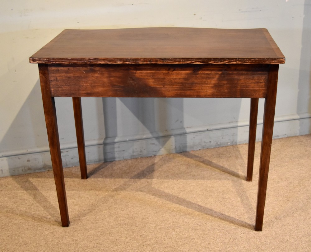 A George III mahogany dressing table featuring a serpentine front, three drawers with brass ring handles, crossbanded inlay, and four square tapered legs. View VII