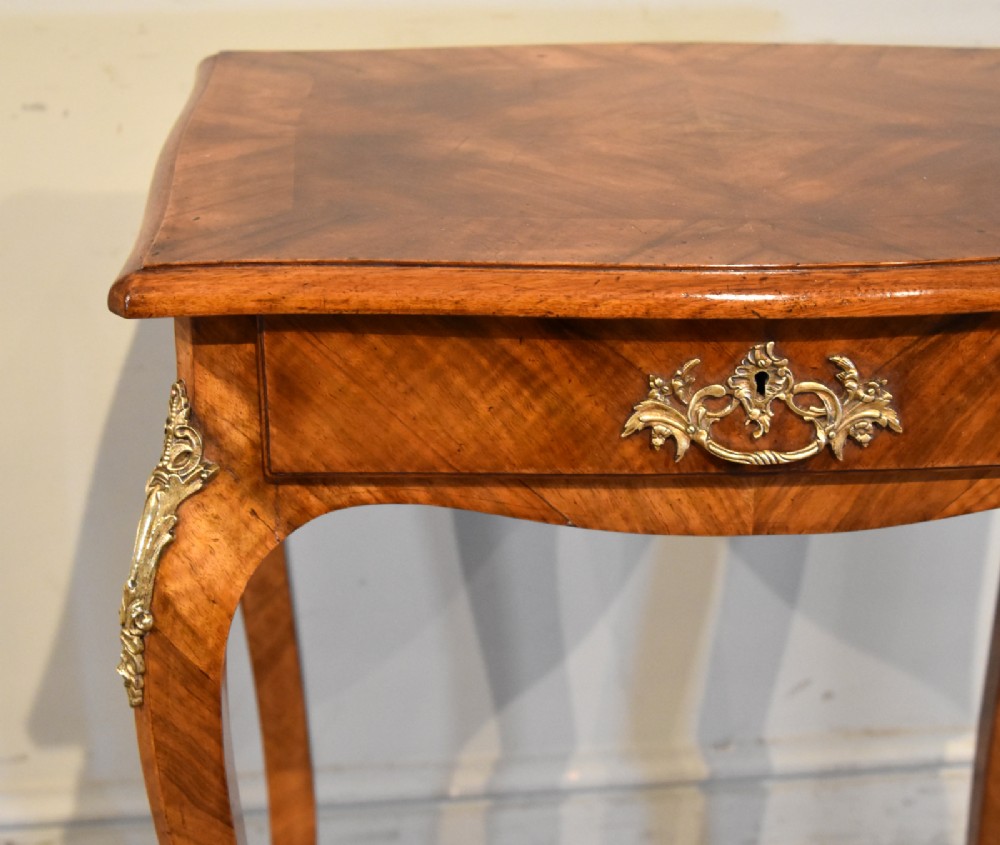 A 19th-century French walnut work table featuring curved cabriole legs, brass knee and foot mounts, a single front drawer with an ornate handle, and matched wood veneer. View V