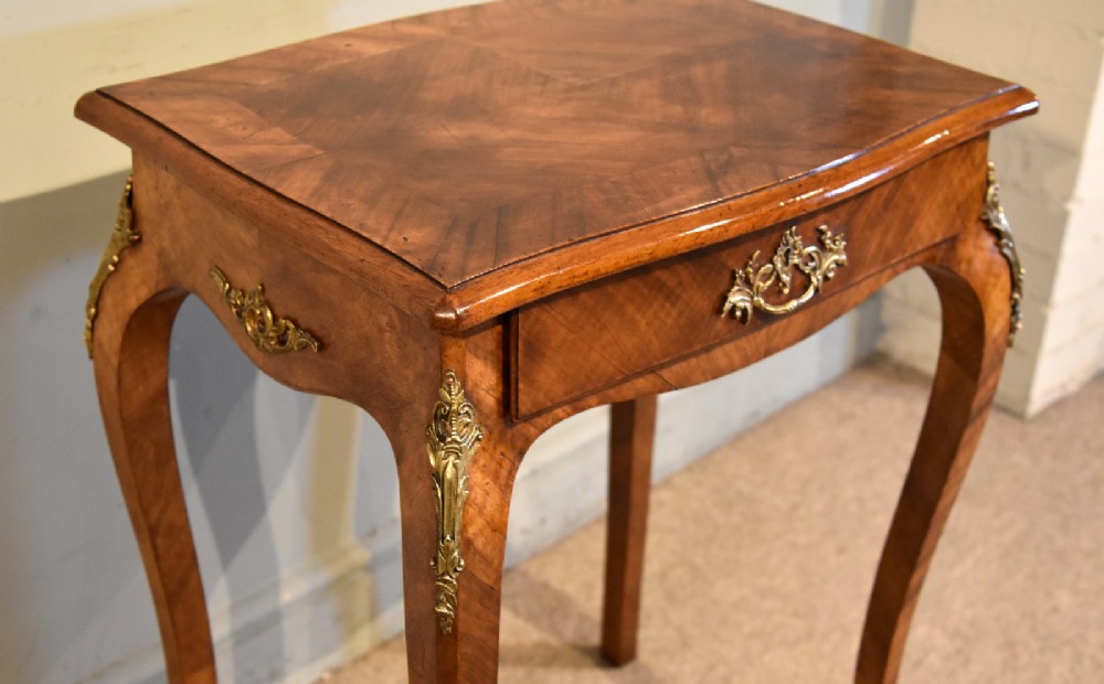A 19th-century French walnut work table featuring curved cabriole legs, brass knee and foot mounts, a single front drawer with an ornate handle, and matched wood veneer. View VI