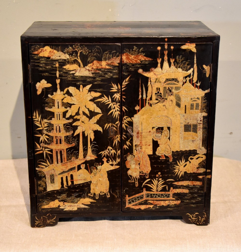 A rectangular black lacquer table cabinet decorated with detailed gold chinoiserie depictions of pagodas, figures, and foliage.