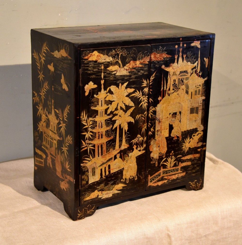 A rectangular black lacquer table cabinet decorated with detailed gold chinoiserie depictions of pagodas, figures, and foliage. View II