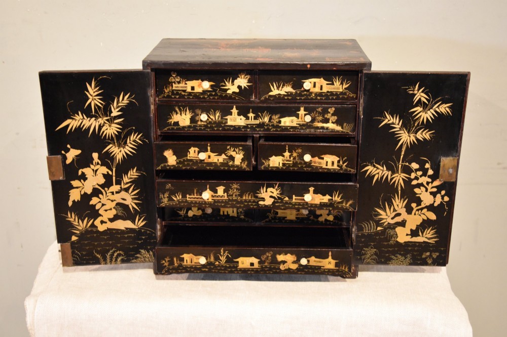 A rectangular black lacquer table cabinet decorated with detailed gold chinoiserie depictions of pagodas, figures, and foliage. View IV
