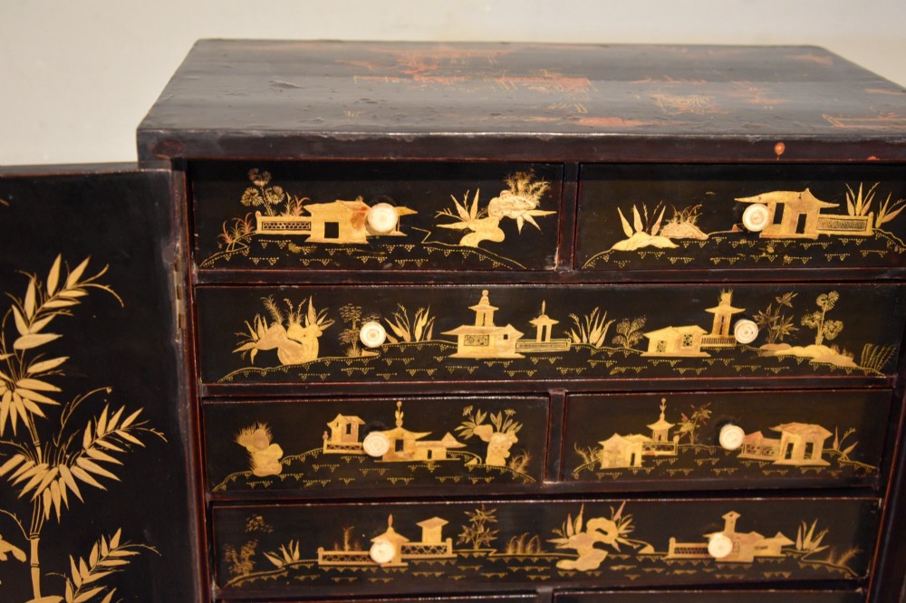 A rectangular black lacquer table cabinet decorated with detailed gold chinoiserie depictions of pagodas, figures, and foliage. View V
