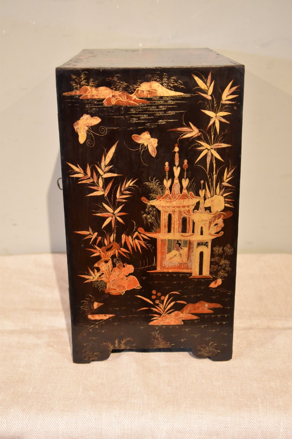 A rectangular black lacquer table cabinet decorated with detailed gold chinoiserie depictions of pagodas, figures, and foliage. View VI