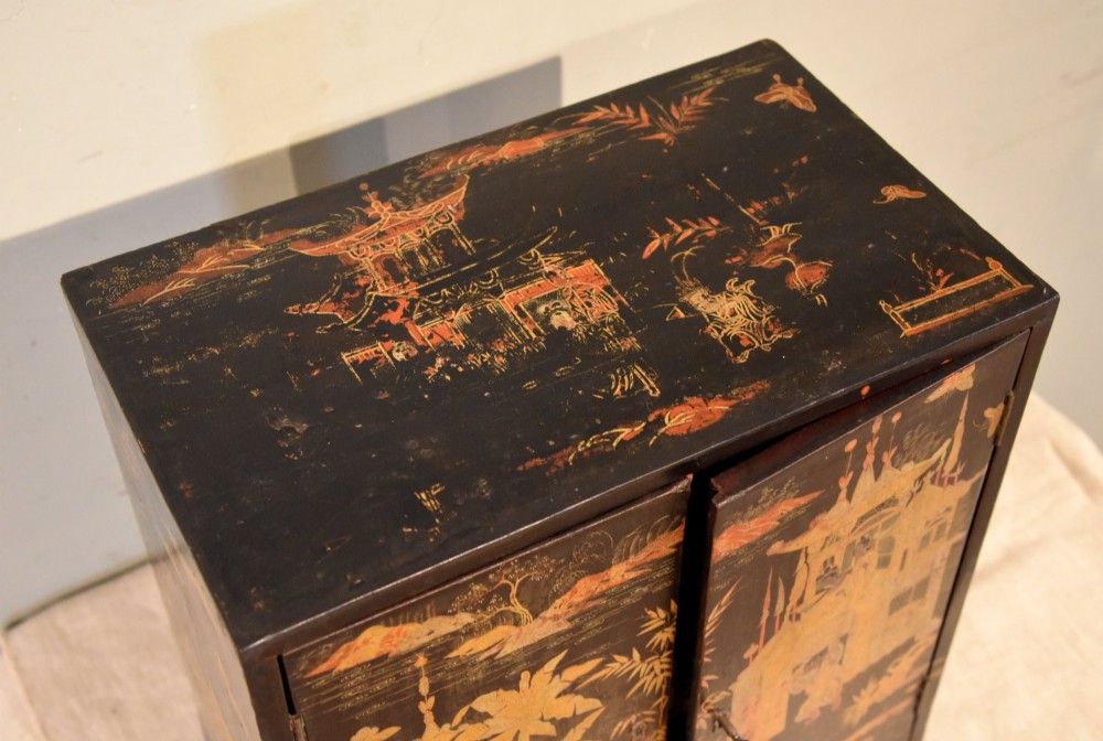 A rectangular black lacquer table cabinet decorated with detailed gold chinoiserie depictions of pagodas, figures, and foliage. View VII