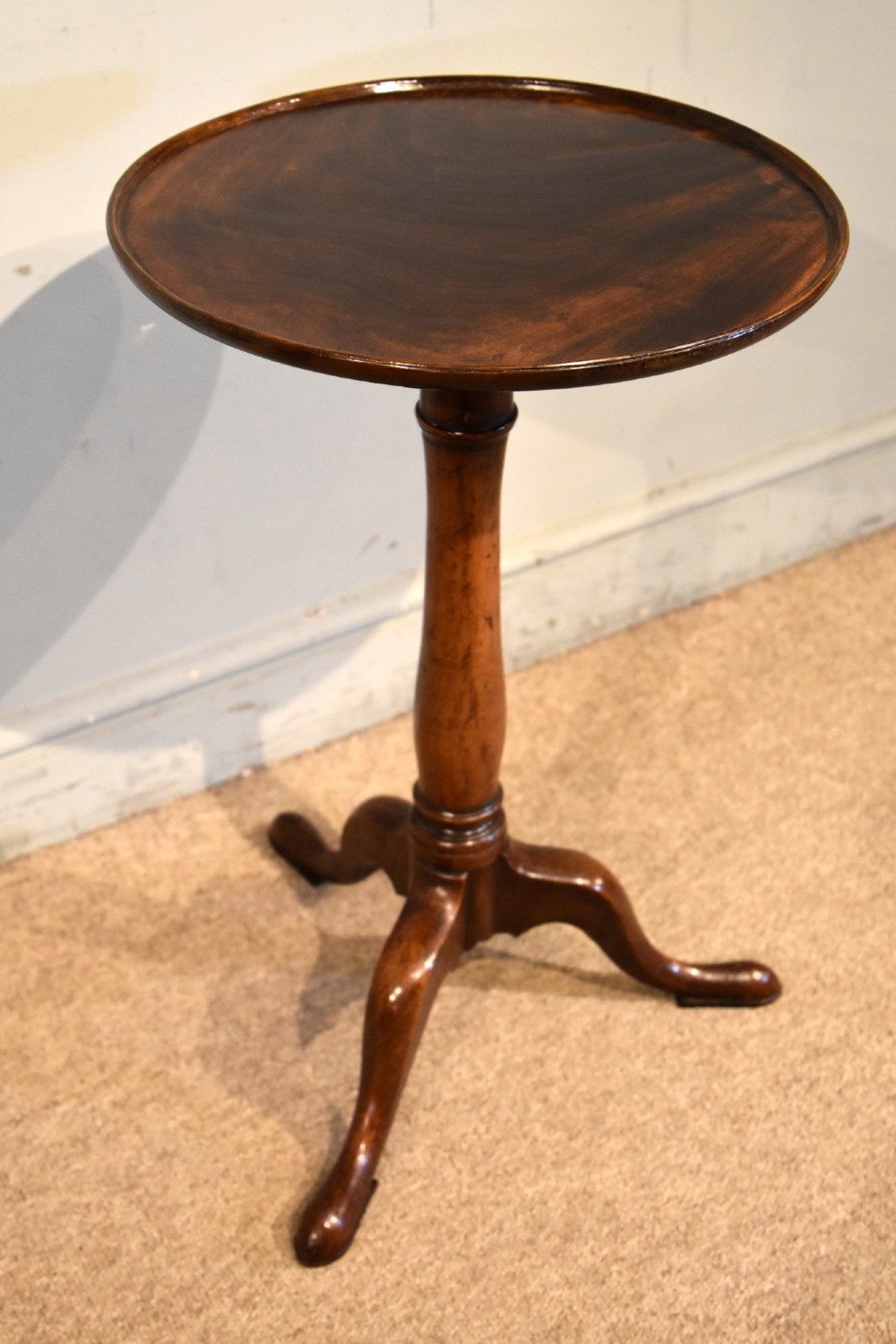 A George III mahogany tripod table featuring a circular dish top supported on a turned baluster column with three splayed legs. View II