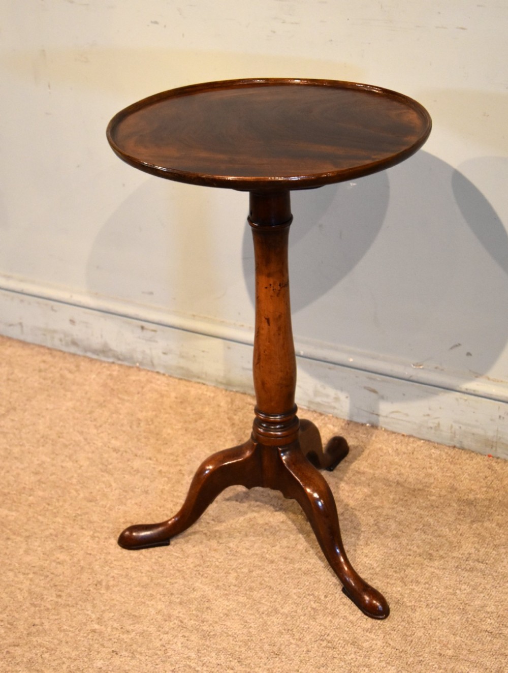 A George III mahogany tripod table featuring a circular dish top supported on a turned baluster column with three splayed legs. View III