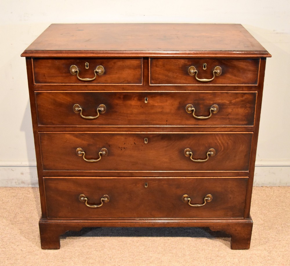 An 18th-century Georgian mahogany chest of drawers featuring two short over three long graduated drawers, brass swan-neck handles, keyhole escutcheons, and bracket feet.