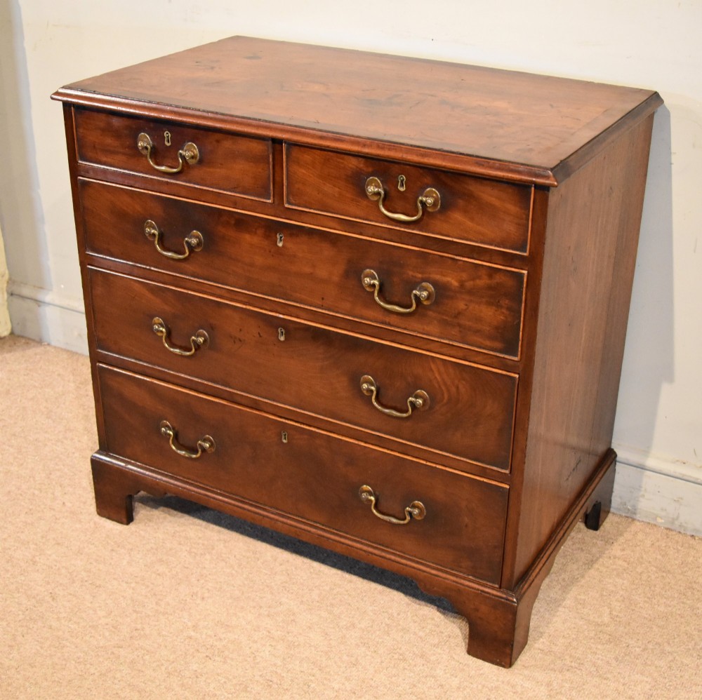 An 18th-century Georgian mahogany chest of drawers featuring two short over three long graduated drawers, brass swan-neck handles, keyhole escutcheons, and bracket feet. View II