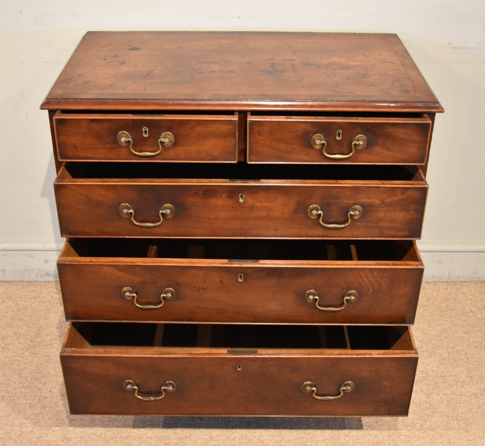 An 18th-century Georgian mahogany chest of drawers featuring two short over three long graduated drawers, brass swan-neck handles, keyhole escutcheons, and bracket feet. View III