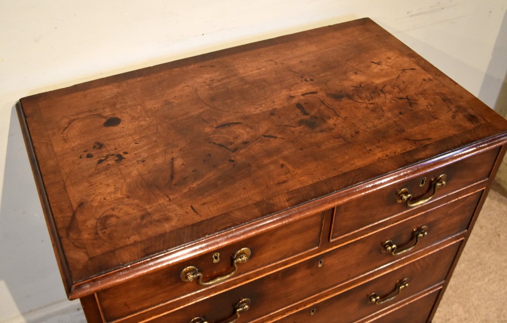 An 18th-century Georgian mahogany chest of drawers featuring two short over three long graduated drawers, brass swan-neck handles, keyhole escutcheons, and bracket feet. View V