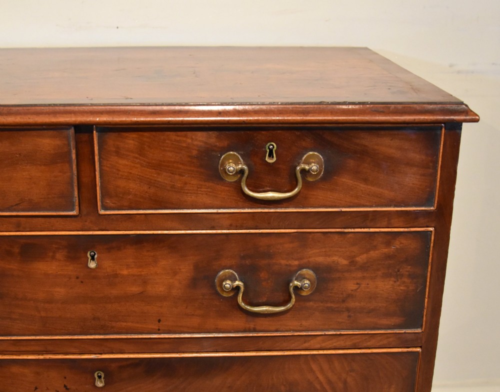 An 18th-century Georgian mahogany chest of drawers featuring two short over three long graduated drawers, brass swan-neck handles, keyhole escutcheons, and bracket feet. View VI
