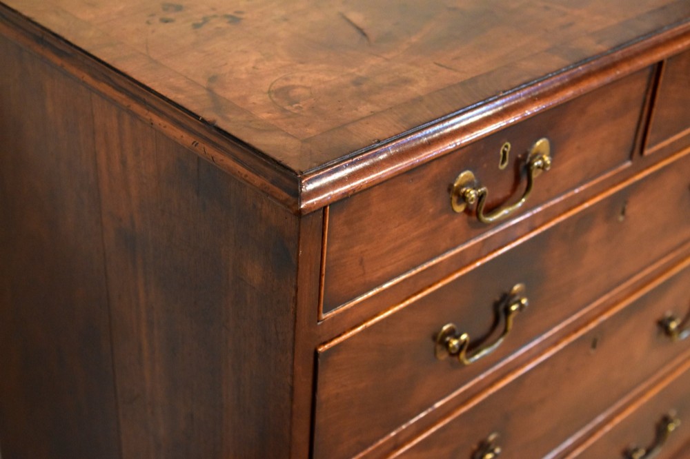 An 18th-century Georgian mahogany chest of drawers featuring two short over three long graduated drawers, brass swan-neck handles, keyhole escutcheons, and bracket feet. View VII