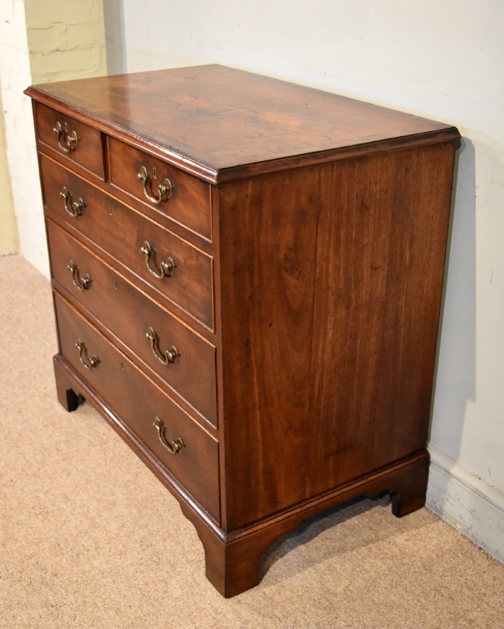 An 18th-century Georgian mahogany chest of drawers featuring two short over three long graduated drawers, brass swan-neck handles, keyhole escutcheons, and bracket feet. View VIII