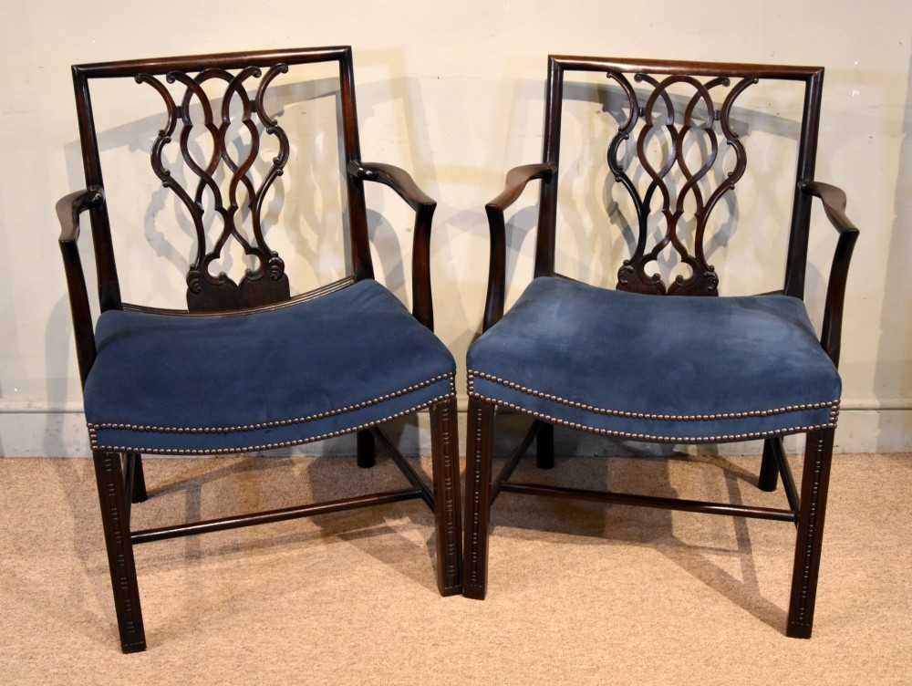 A matched pair of dark mahogany Chippendale style armchairs with intricate pierced back splats and blue velvet upholstered seats with brass stud detailing.