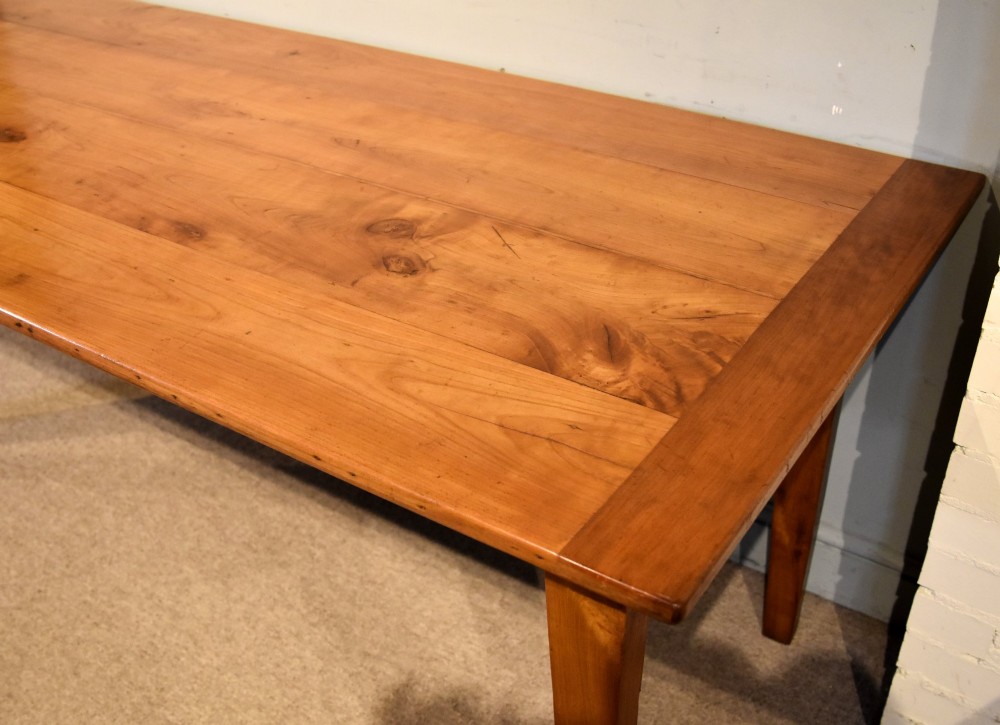 A nineteenth-century French cherry wood farmhouse table featuring a rectangular planked top, breadboard ends, a simple apron, and square tapered legs. View IV