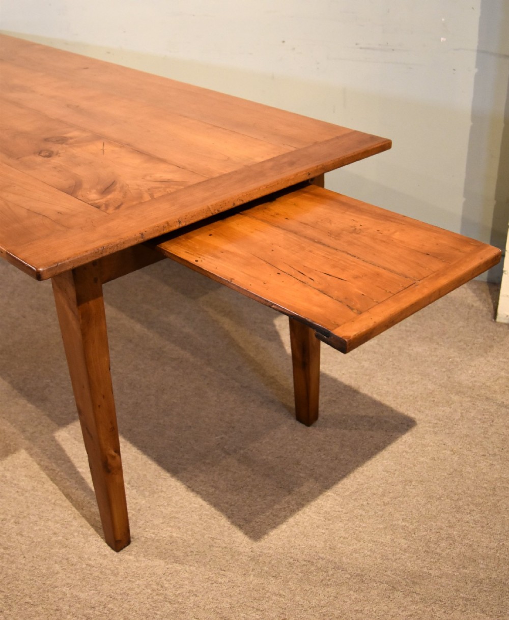 A nineteenth-century French cherry wood farmhouse table featuring a rectangular planked top, breadboard ends, a simple apron, and square tapered legs. View V
