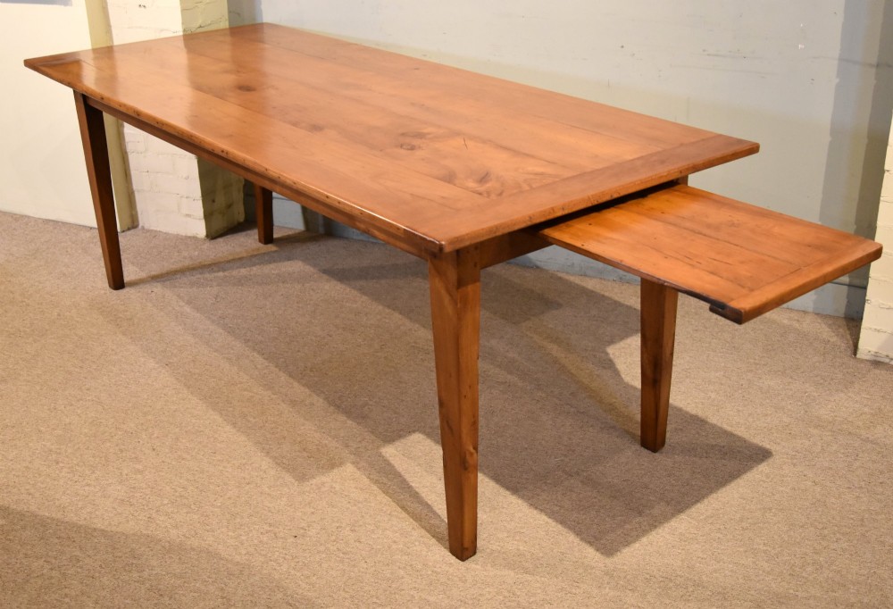 A nineteenth-century French cherry wood farmhouse table featuring a rectangular planked top, breadboard ends, a simple apron, and square tapered legs. View VI