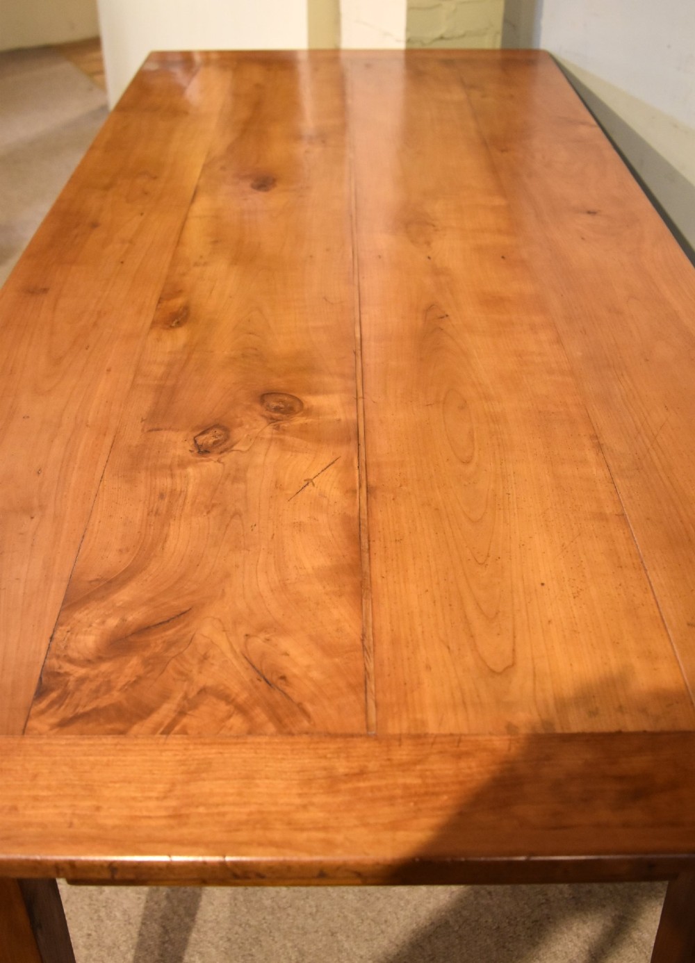 A nineteenth-century French cherry wood farmhouse table featuring a rectangular planked top, breadboard ends, a simple apron, and square tapered legs. View VIII