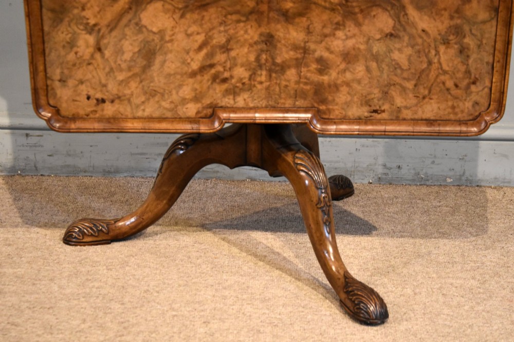 A Victorian tilt-top supper table made from burr walnut featuring a shaped top and a carved tripod pedestal base. View II